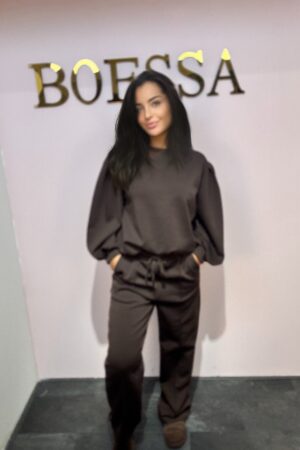 Vrouw poseert in een zwarte tweedelige jogging set met pofmouwen, bandplooi en elastische tailleband, geschikt tot maat 42.