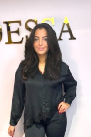 Zwarte satijnen blouse voor dames met kraag, knoopsluiting en asymmetrisch kanten detail aan de onderkant.