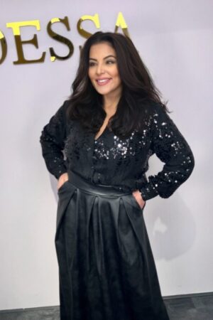 Model draagt een oversized blouse met pailletten in een feestelijke setting, gecombineerd met een zwarte rok