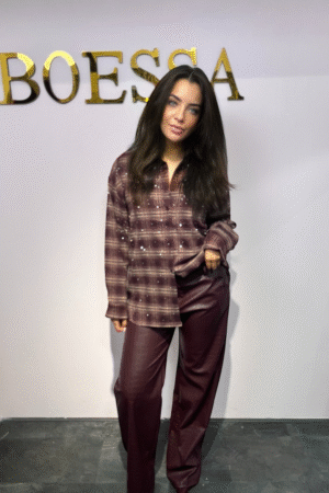 Model draagt een vegan leren croco pantalon in bordeaux met rechte pijp, steekzakken en high waist pasvorm.